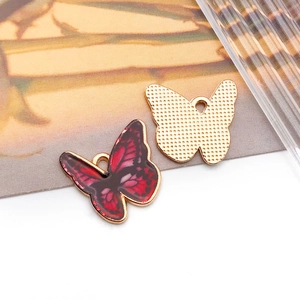 Detailed view of red gradient butterfly charm with gold metal edges for DIY jewelry making