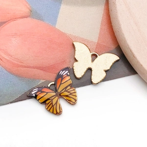 Vue détaillée de breloques papillons dorées et pendentifs en émail orange pour bijoux