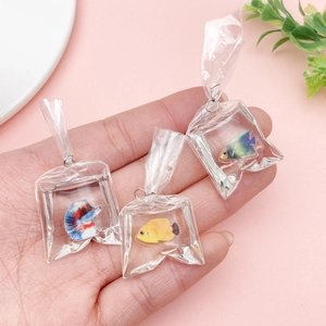 Miniature resin goldfish water bag pendants for DIY jewelry and keychains on pink background