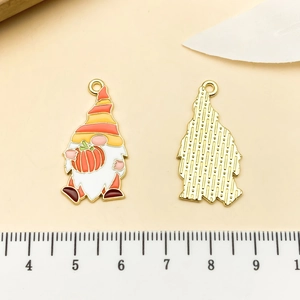 Detailed view of enamel gnome pendants with pumpkin and textured gold back for jewelry DIY