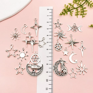 Close-up of assorted silver alloy celestial pendants with stars and moons on a pink surface