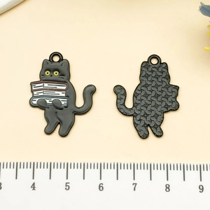 Vue détaillée du pendentif chat en émail noir montrant l'avant et l'arrière avec échelle