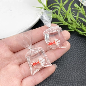 Handheld macro view of a creative resin goldfish bag pendant for DIY keychains