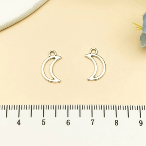 Detail of two silver moon charms with measuring scale for size reference