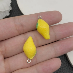 Vue macro d'un pendentif citron en résine 3D avec feuille verte et crochet sur la main