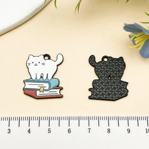 Détail d'un pendentif chat lisant sur des livres avec échelle de mesure précise