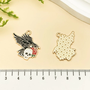 Detail of gothic raven and skull enamel charm with red rose and golden plating