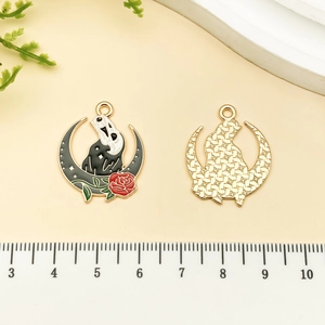 Detailed view of Gothic moon pendants with Scream mask and rose next to a ruler