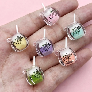 Detailed view of six colorful mini resin coffee cup charms held in a palm for DIY crafts
