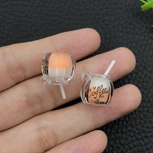 Close-up of luminous resin coffee cup charms with orange white layers and straw