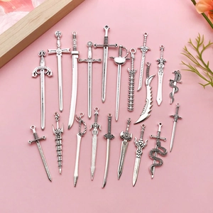 Flat lay view of various miniature antique silver alloy sword pendants for DIY jewelry making