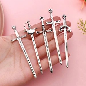 Five pieces of medieval style silver sword pendants held in hand with pink background