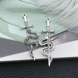 Detailed antique silver snake and sword charms on leather background for jewelry DIY