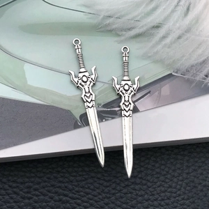 Macro detail of antique silver sword pendants with intricate hilt and top hanging loop