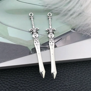 Detailed macro view of silver antique sword pendants with intricate carvings for DIY