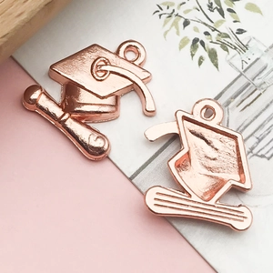 Detailed view of rose gold graduation cap and scroll alloy charms for DIY jewelry making