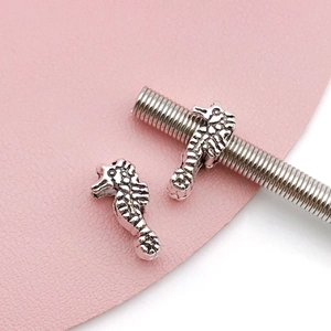 Macro shot of silver seahorse beads on spring wire for DIY bracelet jewelry making