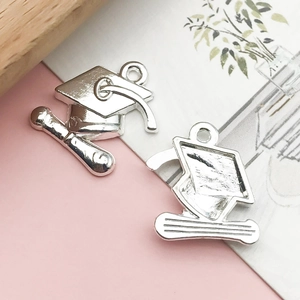 Macro shot of silver graduation cap and scroll alloy charms for DIY jewelry making