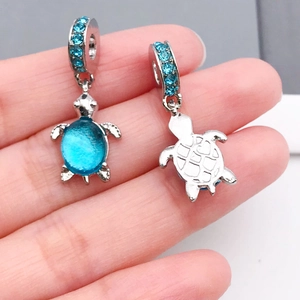 Dettaglio macro dei ciondoli tartaruga in argento con gemme blu e cristalli luminosi