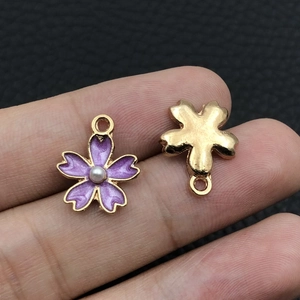 Macro detail of purple enamel flower pendant with pearl center and golden alloy ring