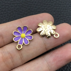Detail of purple enamel sunflower and golden metal charms for DIY jewelry making