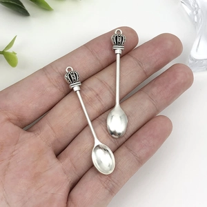 Detail view of retro silver crown spoon pendants held in hand for jewelry making diy