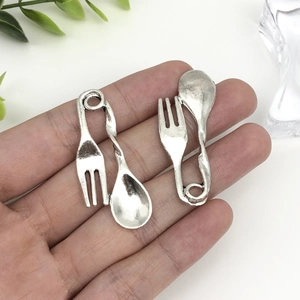 Detail view of antique silver fork and spoon charms for DIY jewelry and keychain accessories