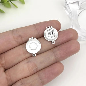 Detailed macro view showing the front and back of a vintage silver alloy cutlery pendant