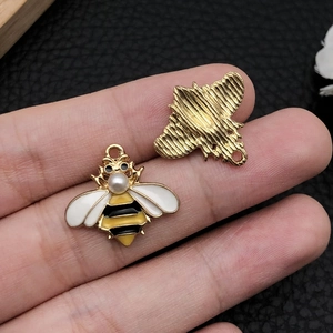 Makro-Detail von Emaille-Bienenanhängern mit Perleneinlage und goldener Rückseite