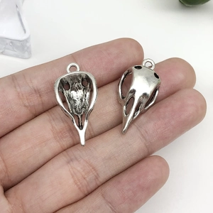 Gros plan de pendentifs tête d'oiseau argentés vintage sur une main pour l'échelle