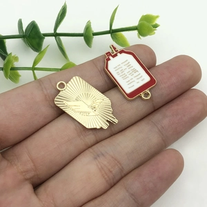 Dettaglio di ciondoli medici DIY con piastra dorata e charm a sacca di sangue smaltata