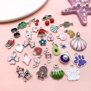 Assorted colorful DIY enamel flower and fruit pendants on pink aesthetic background