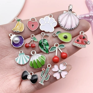 Macro detail of assorted colorful enamel alloy charms held in hand for DIY jewelry making