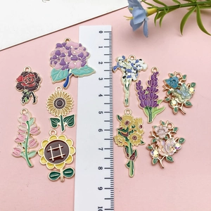 Λεπτομέρεια από σμαλτωμένα μενταγιόν λουλούδια και πεταλούδες με χάρακα σε ροζ φόντο
