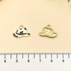 Vue macro d'un pendentif chapeau de cowboy en émail imprimé vache et finition dorée
