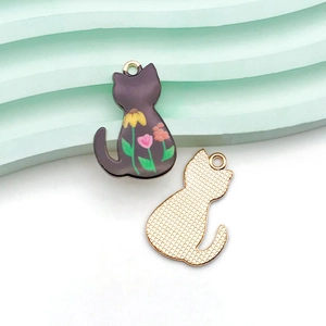 Dettaglio fronte e retro di ciondoli a gatto in smalto nero con base a maglia dorata