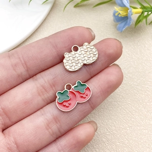 Detail view of cherry fruit charms with red enamel and gold-tone metal plating
