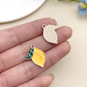 Detailed view of handmade enamel lemon charms with golden alloy backing for DIY jewelry