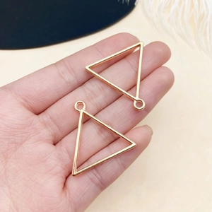 Close-up of golden triangular hollow frames for DIY jewelry pendants and earrings