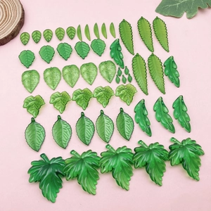 Detalle de varios colgantes de hojas de acrílico verde para creación de joyas