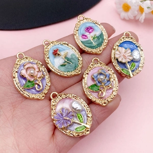 Pendentifs ovales en émail avec bordure dorée et détails de perles dans la main
