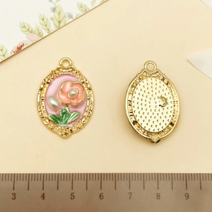 Détail macro du pendentif floral ovale avec émail rose, plaqué or et référence de taille