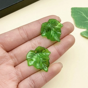 Vista detallada de colgantes de hojas acrílicas verde oscuro con nervaduras para joyería DIY