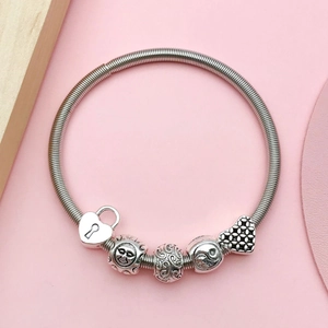 Bracciale con ciondoli argento, lucchetto a cuore e simboli yin yang su sfondo rosa