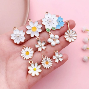 Vue détaillée de pendentifs fleurs en émail blanc et bleu avec bordure en métal doré