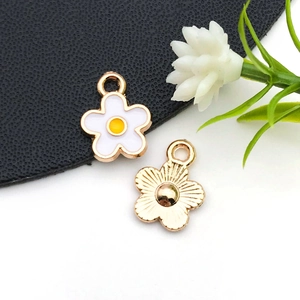 Détails macro des breloques fleurs en émail blanc et plaqué or pour bijoux DIY