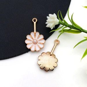 Détail de breloques marguerites en émail blanc avec perles roses et dos doré texturé