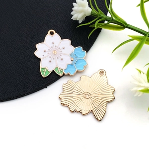 Détails des pendentifs en émail fleur blanche et bleue montrant le recto et le verso