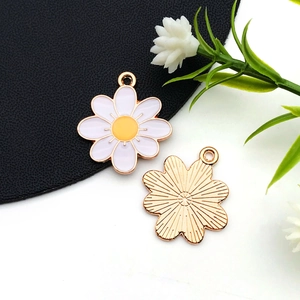 Détails macro des breloques fleurs blanches et envers doré texturé pour bijoux DIY