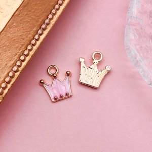 Vue détaillée des pendentifs couronne avec émail rose et texture creuse dorée